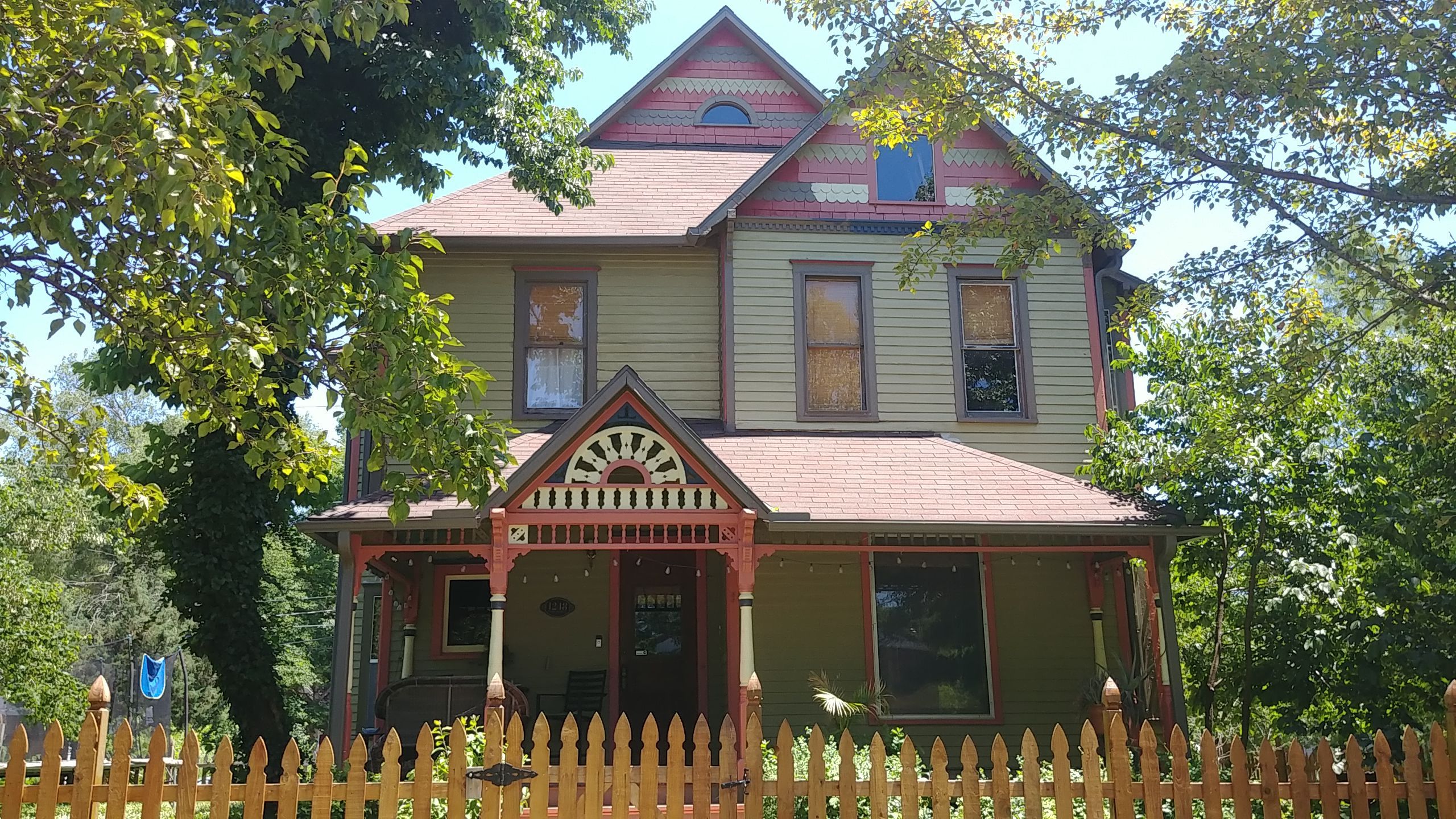 Victorian home exterior painting in Lawrence, KS, featuring green and red colors.