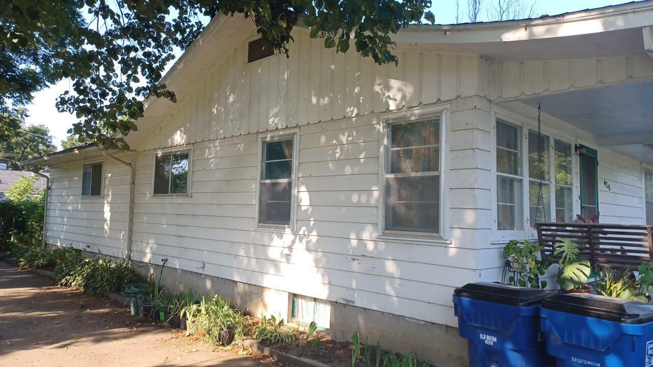 White house exterior in Lawrence, KS with peeling paint needing house painting services.