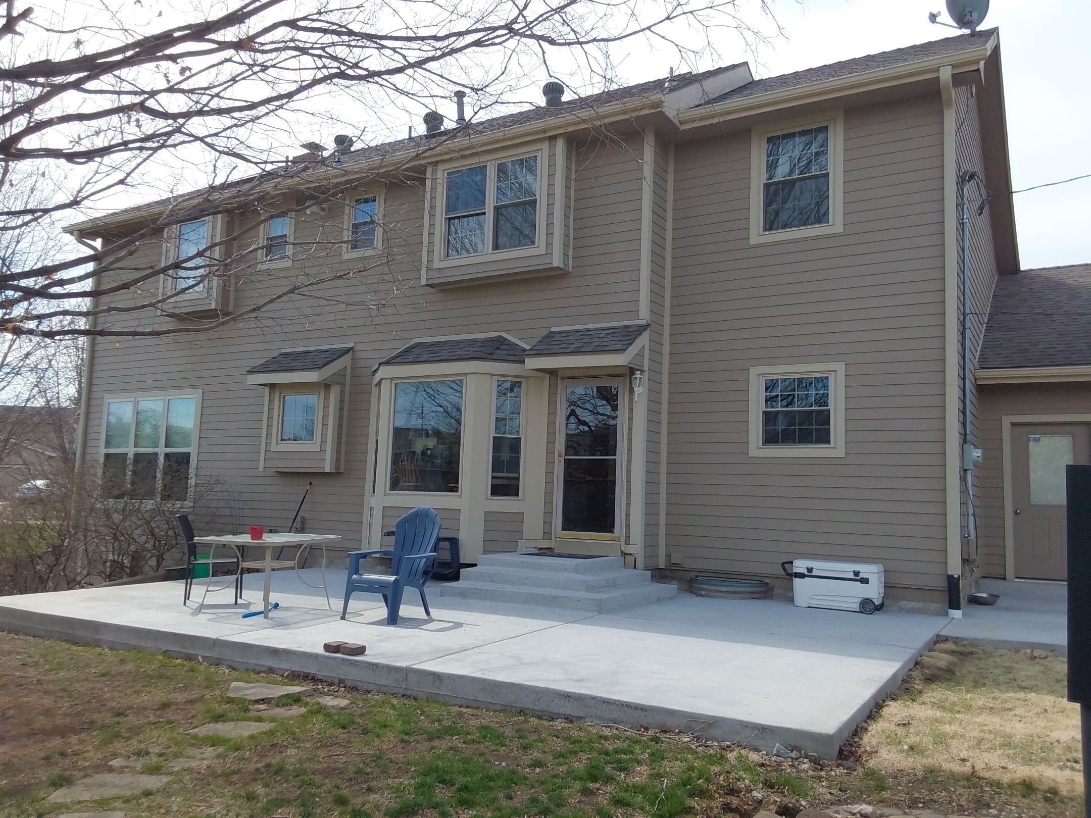 Tan house exterior with bay windows and concrete patio in Topeka, KS.