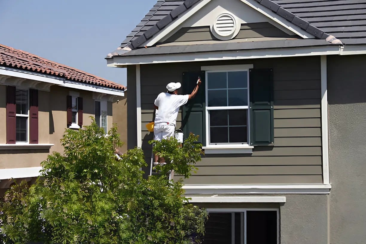 Exterior painter in Leawood, KS, applying paint to a residential exterior