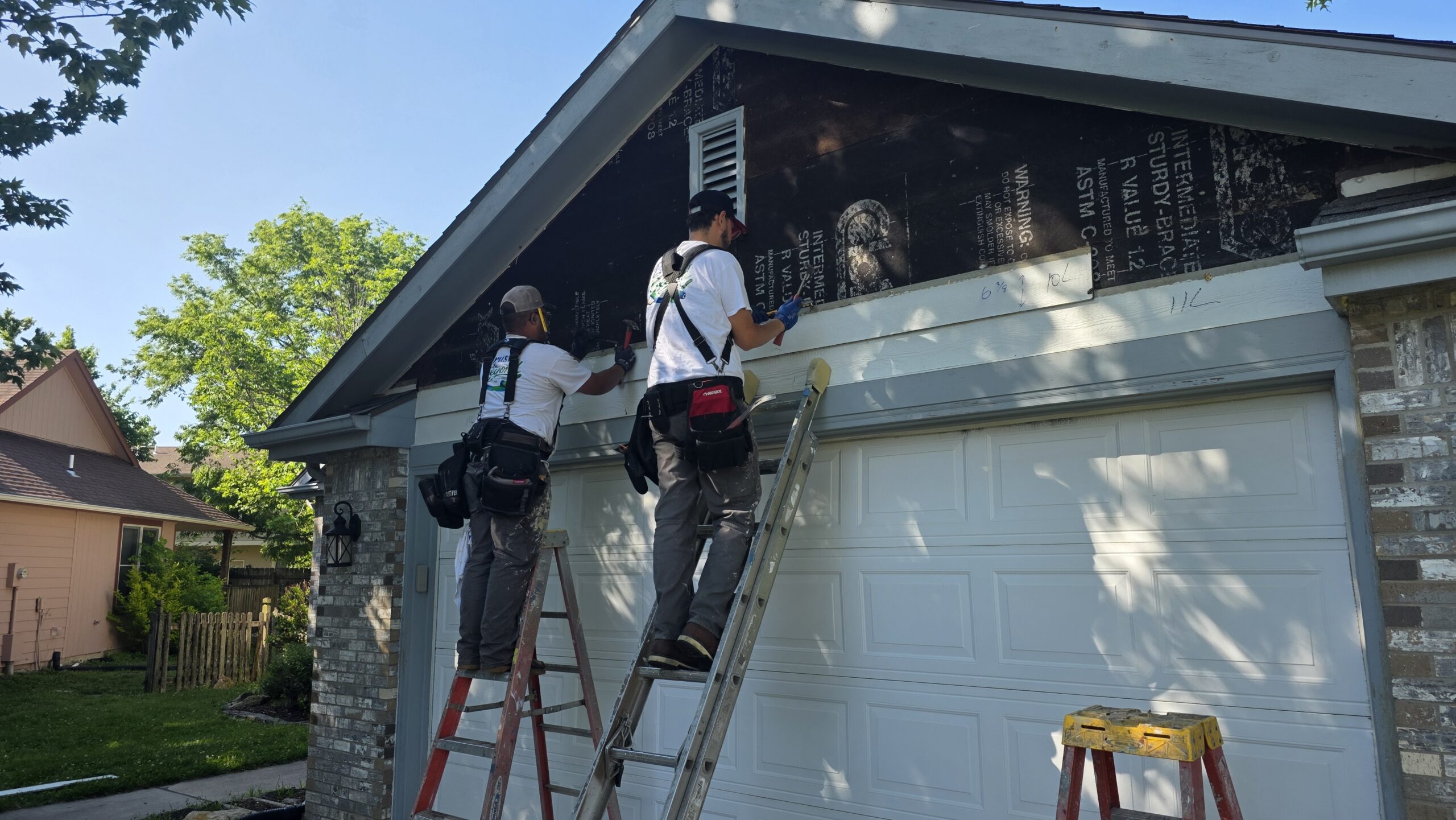 Carpenters repair wood rot on a garage exterior in Topeka, KS.