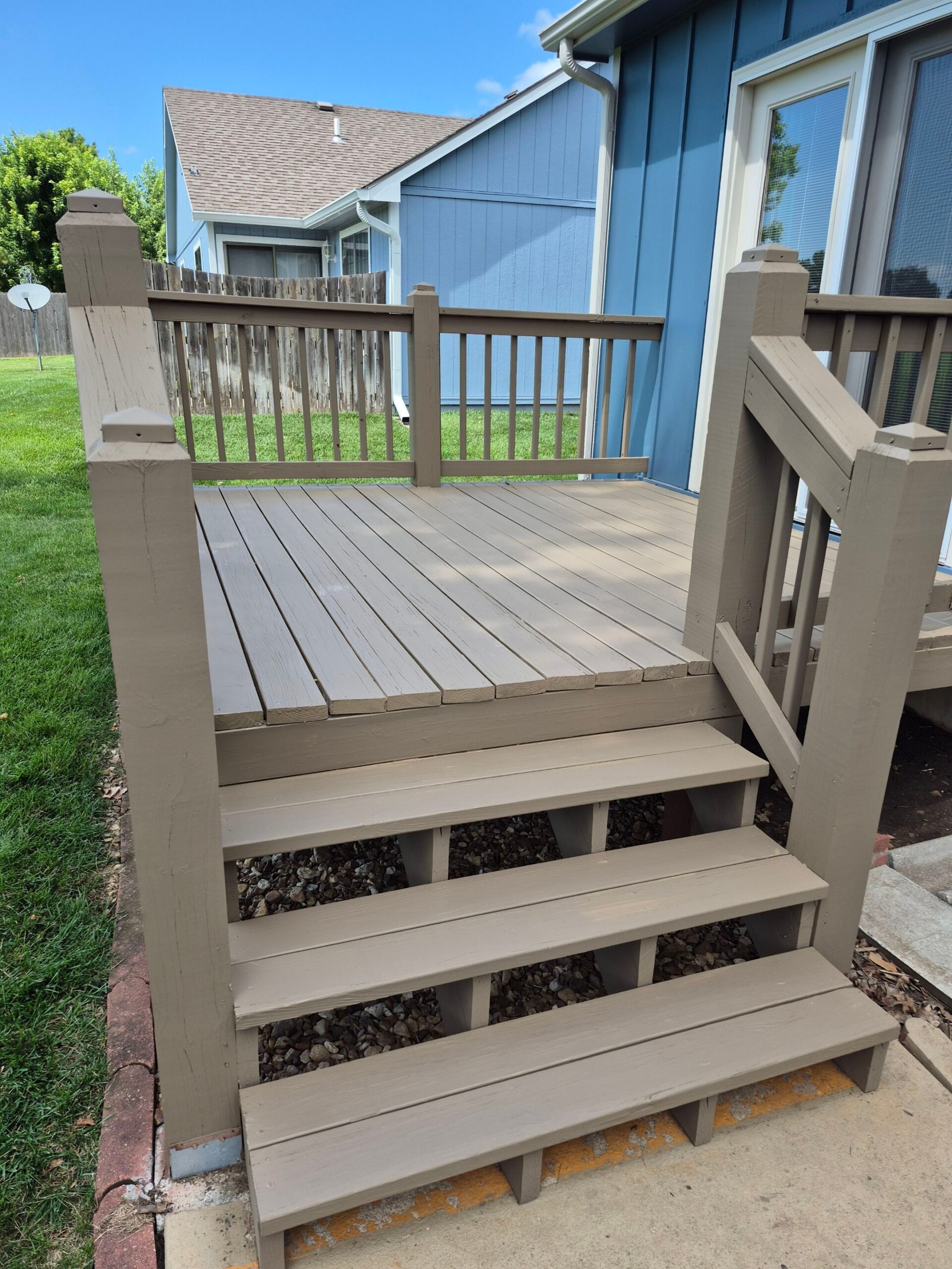 Newly stained deck and stairs in Topeka, Kansas, with a blue house exterior.